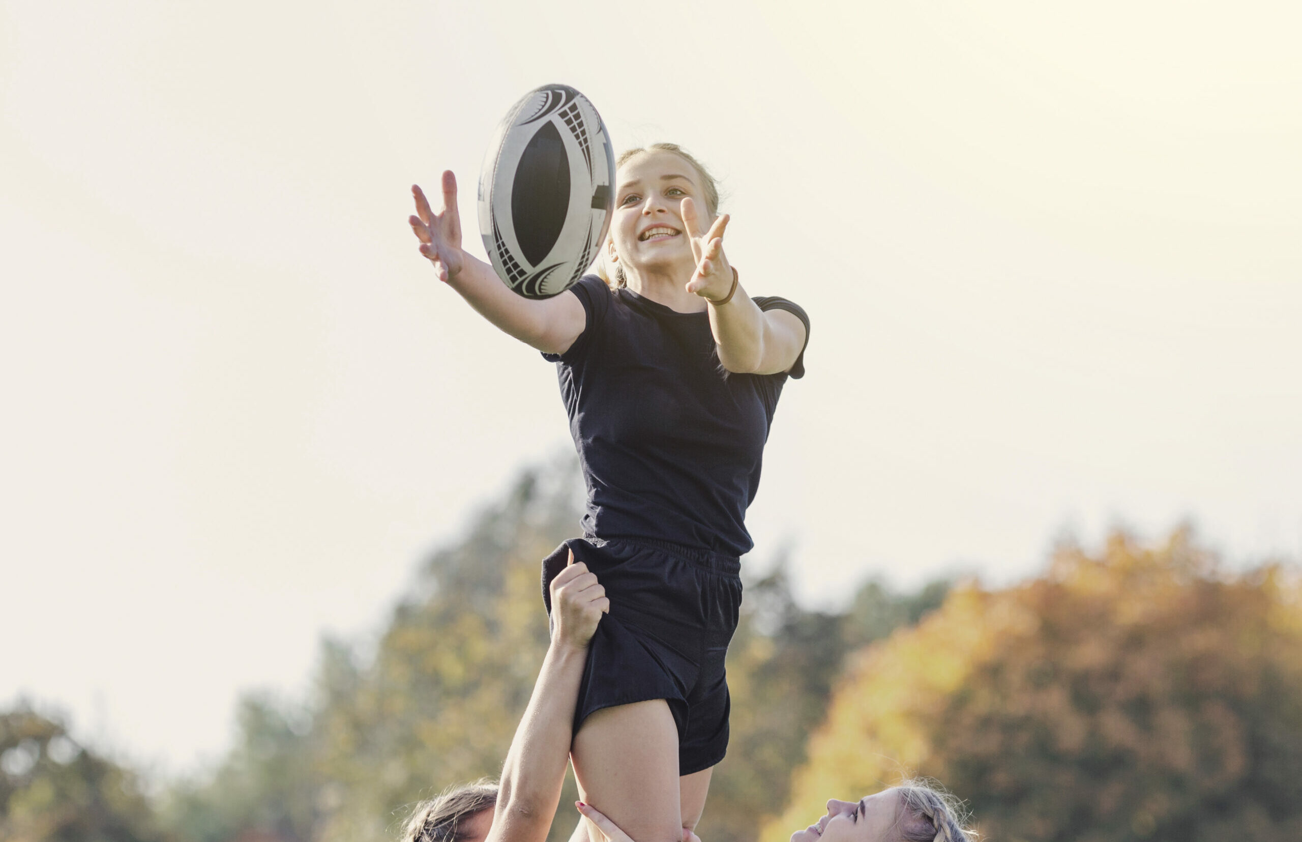 girl catching ball helped by her team mates